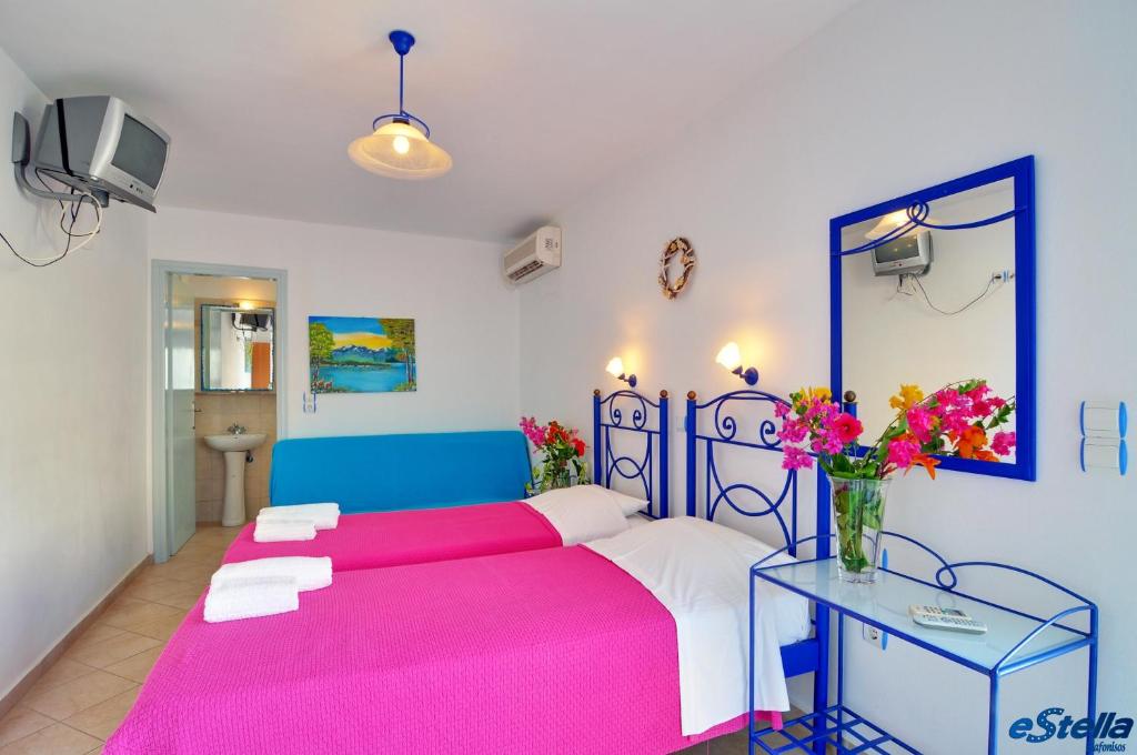 a bedroom with a pink and white bed and a table at Estella Studios in Elafonisos