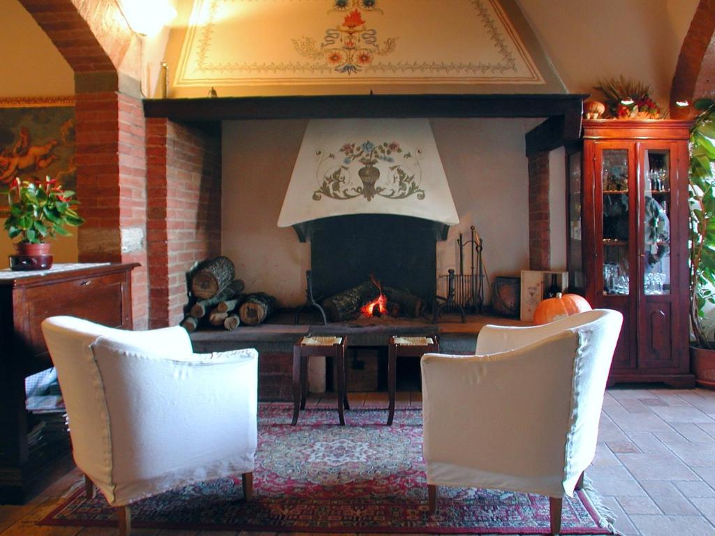 sala de estar con chimenea y 2 sillas blancas en Albergo Il Giglio, en Montalcino