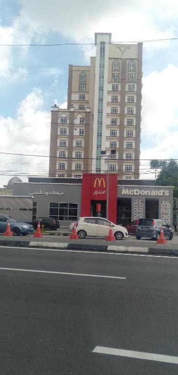 a white car parked in front of a large building at NH Studio Apartment Homestay in Wakaf Che Yeh