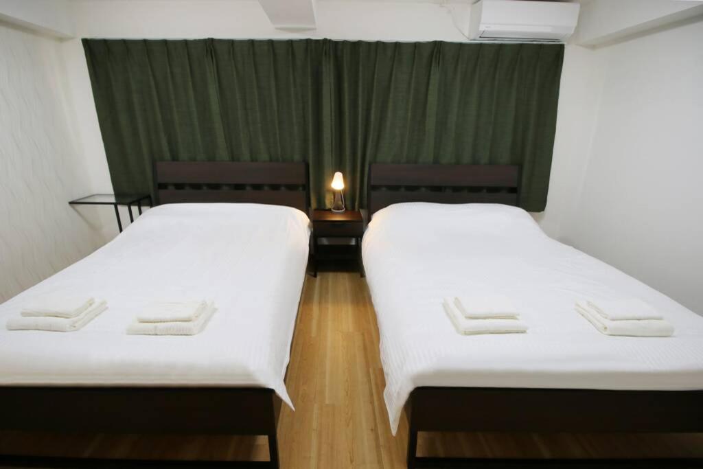 two beds in a room with white sheets at Uhome千駄木静雅民宿旅馆 in Tokyo