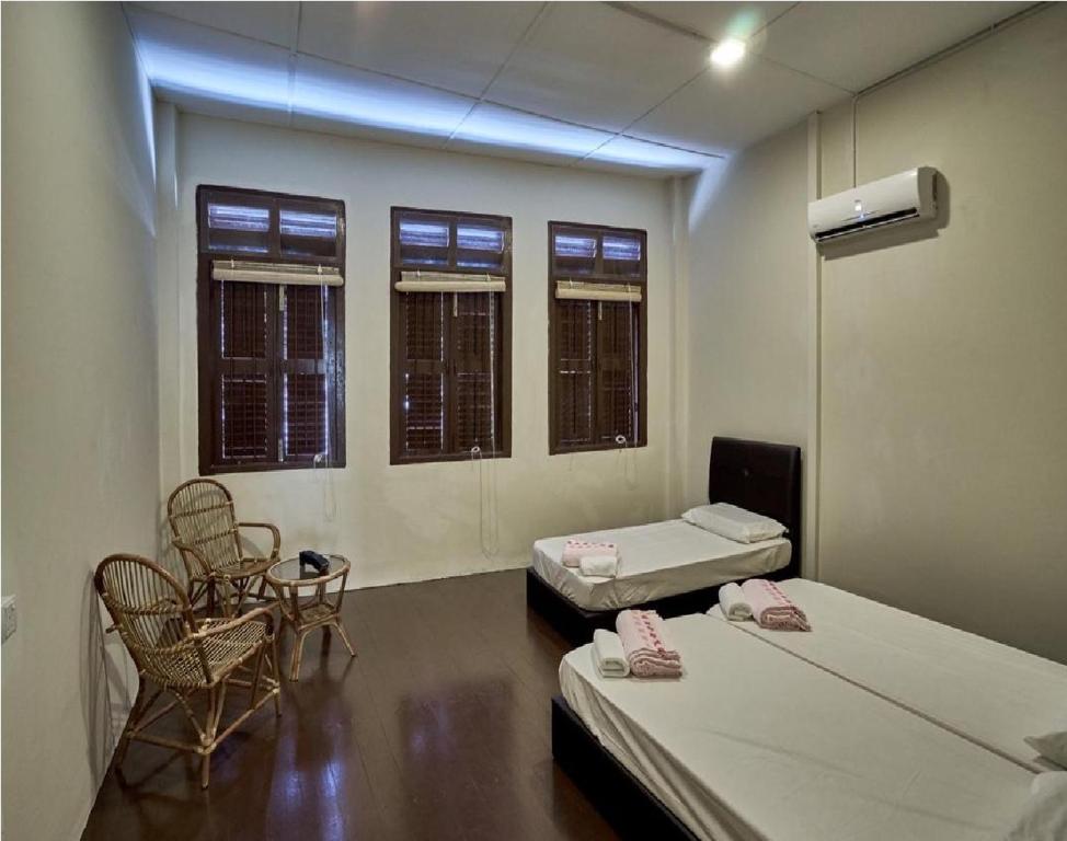 a room with two beds and a table and chairs at We Love GuestHouse in George Town