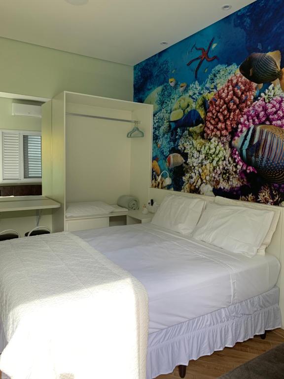- une chambre avec un lit blanc orné d'une peinture murale dans l'établissement Suite Aquarius, à Guarujá