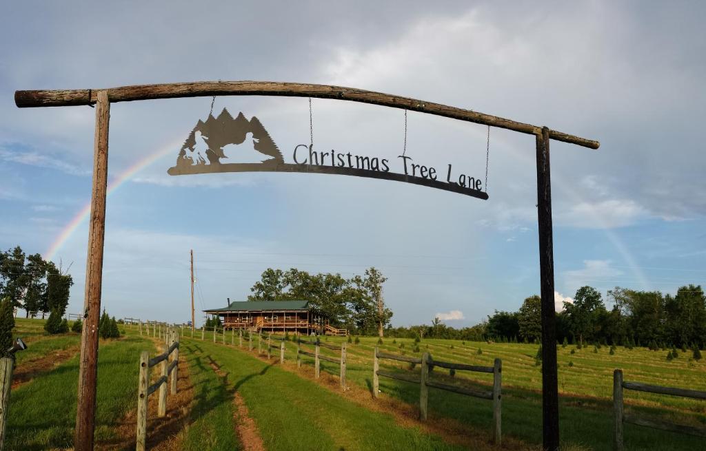 a sign for a christmas tree farm in a field at The Christmas Cabin in Ozark