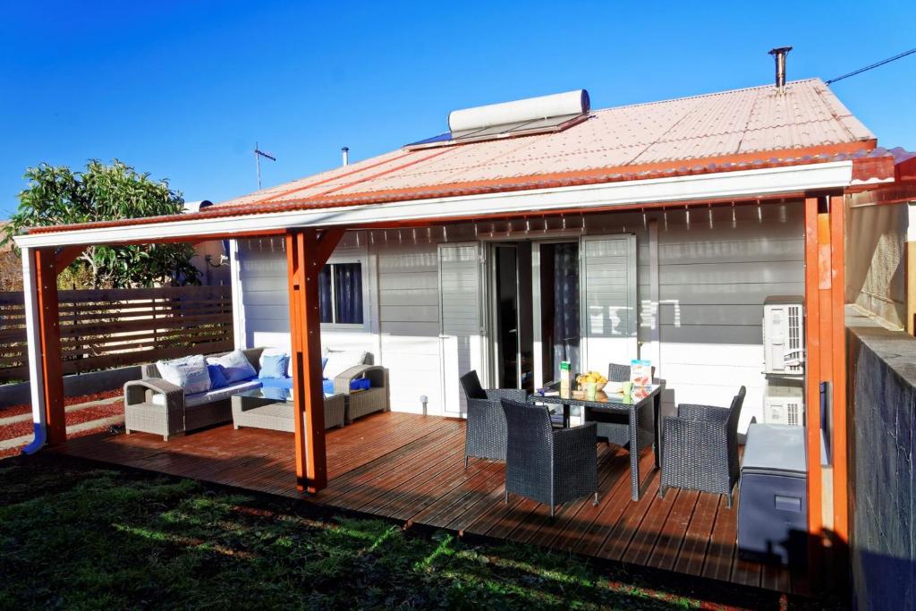 a house with a deck with a table and chairs at Case au pied du volcan in La Plaine des Cafres