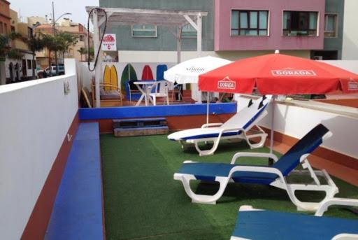 zwei Liegestühle und ein Regenschirm auf dem Dach in der Unterkunft KAKTUS BEACH House in Corralejo