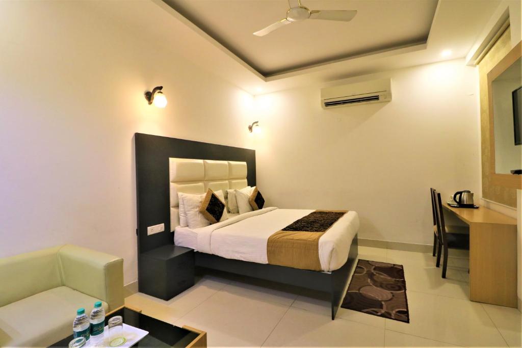 a bedroom with a bed and a desk in a room at Hotel Aeropath Near IGI Airport Delhi in New Delhi