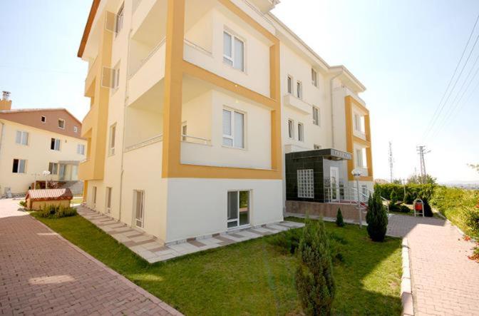 un gran edificio blanco y amarillo en un césped en Fimaj Residence & Hotel, en Kayseri