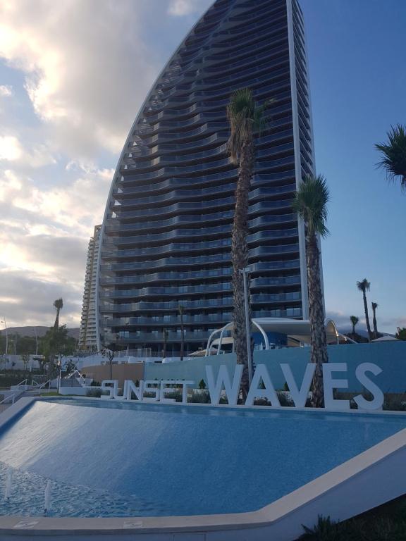 ein großes Gebäude mit Palmen davor in der Unterkunft ROMERO APARTMENTS-SUNSET WAVES-BENIDORM in Benidorm