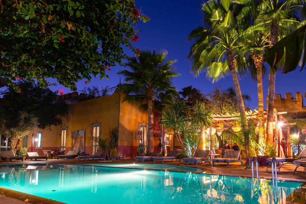 a swimming pool in front of a house with palm trees at Dar Tourkia in Taroudant