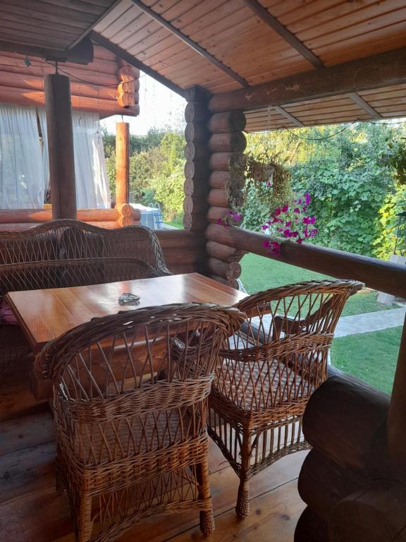 - une terrasse couverte avec une table en bois et 2 chaises dans l'établissement Садиба У Марії, à Polyana