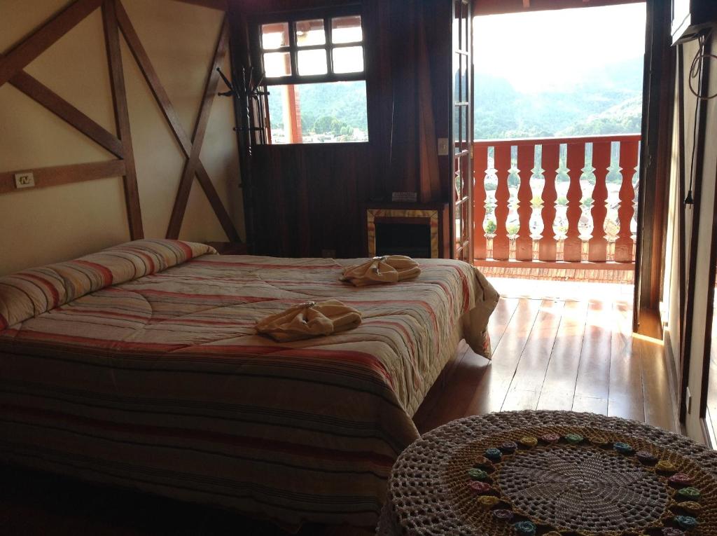 a bedroom with two beds and a large window at Pousada dos Esquilos in Campos do Jordão