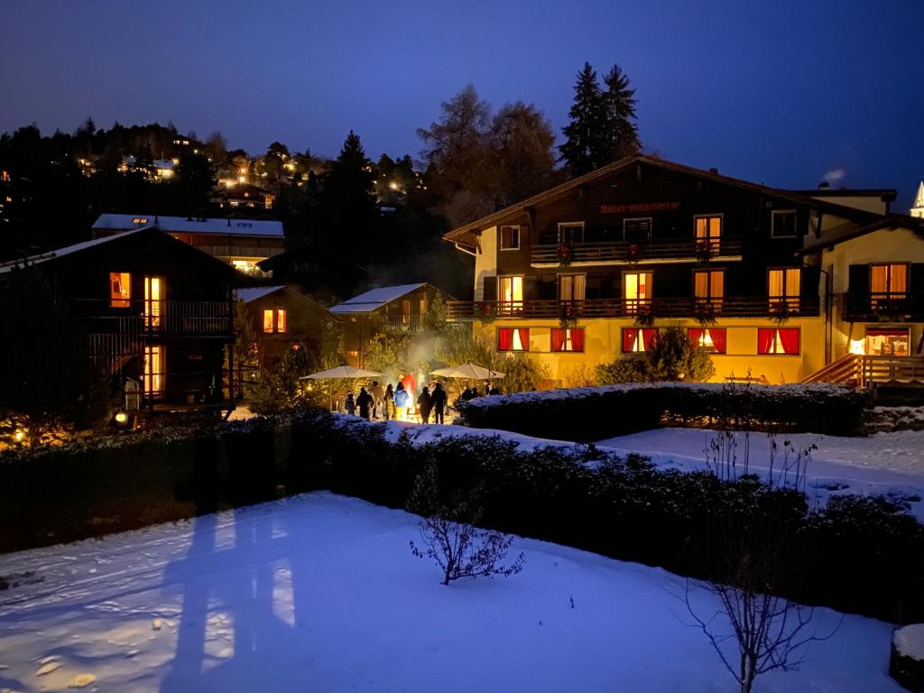 eine Gruppe von Menschen, die nachts im Schnee spazieren gehen in der Unterkunft Victoria Retreat & Spa in Vercorin