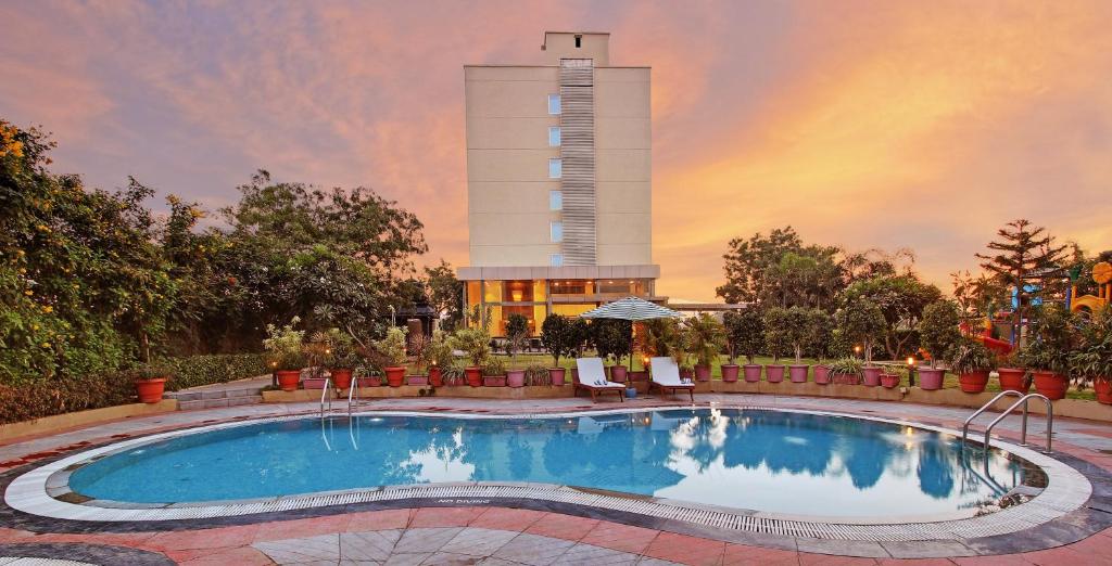 een zwembad met een gebouw op de achtergrond bij Hotel Temple Tree, Shirdi Newly Renovated in Shirdi