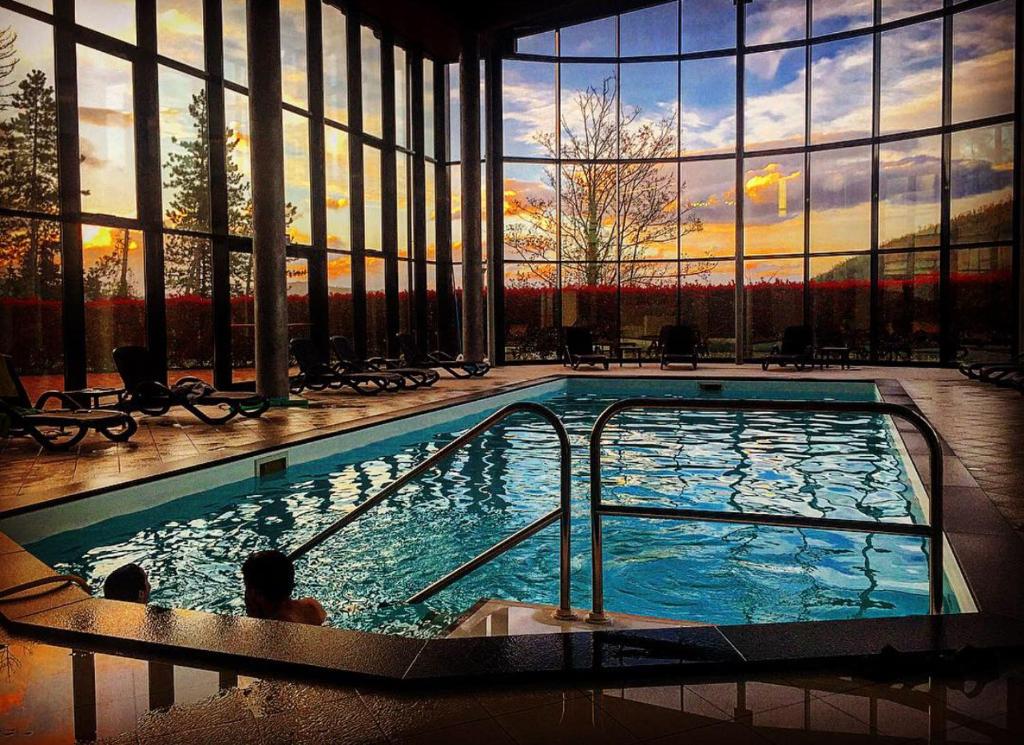 a swimming pool in a building with a large window at Villa Clorè Hotel & Spa in Lama Mocogno