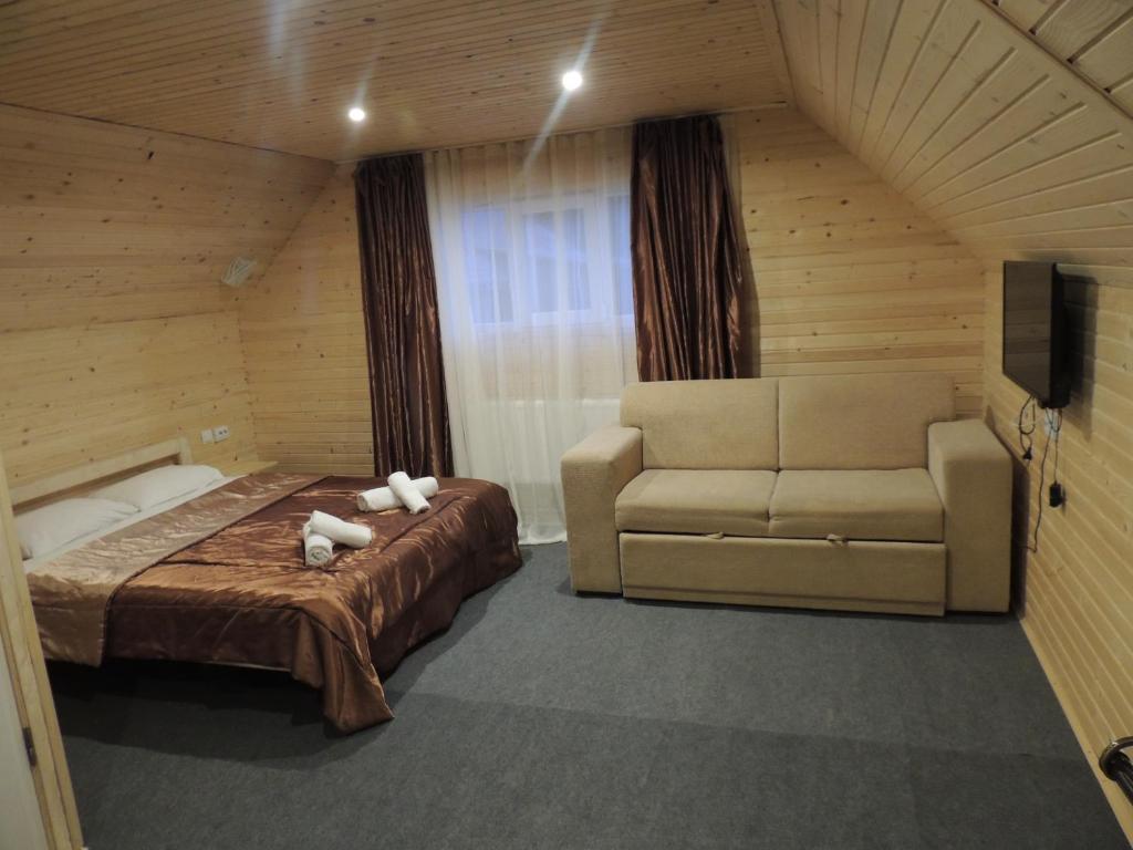 a bedroom with a bed and a couch and a television at Вилла Zlata in Bukovel