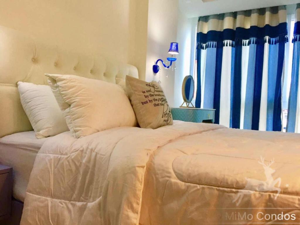 - une chambre avec un grand lit et des rideaux bleus dans l'établissement Grand Avenue Soi Buakhao By Zoom Pattaya 2, à Pattaya (sud)