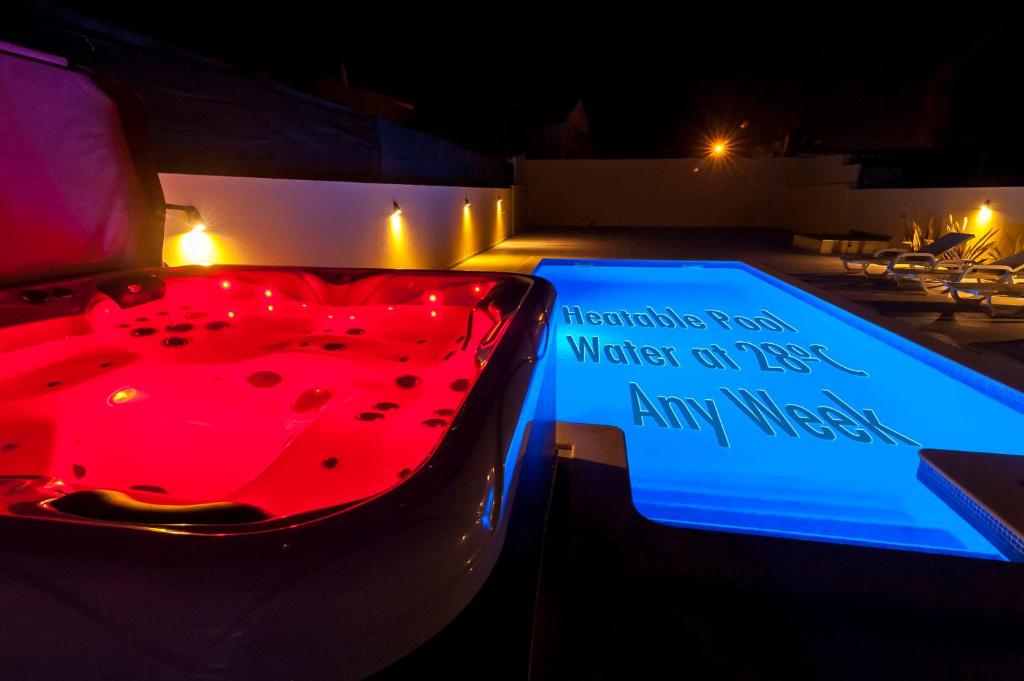 villa Aqua-Jacuzzi-heatable pool-sauna-gym-snooker في ألبوفيرا: وجود سيارة مع وجود لافتة بجانب المسبح ليلا