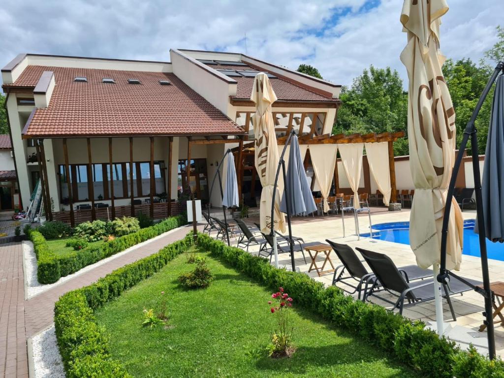 a patio with chairs and umbrellas next to a pool at Pensiunea MedAless in Cernădia