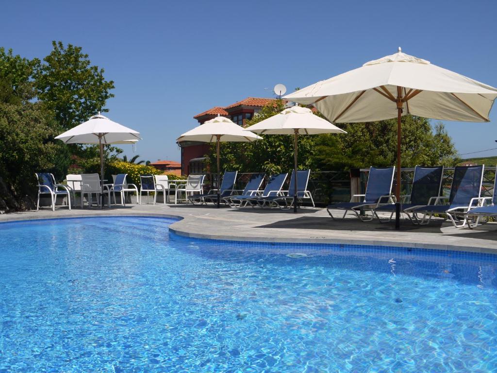 a swimming pool with chairs and umbrellas at Apartamentos Cueto Mazuga I in Po