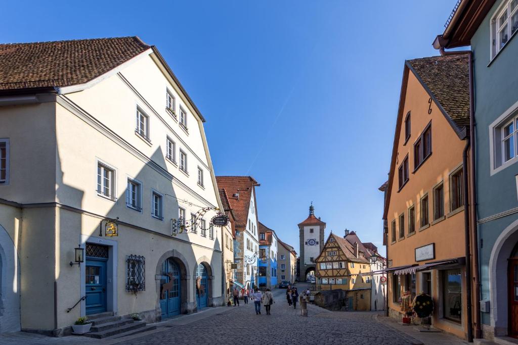 a group of people walking down a street with buildings at Gästehaus Plönlein - Hotel Goldener Hirsch Rothenburg in Rothenburg ob der Tauber