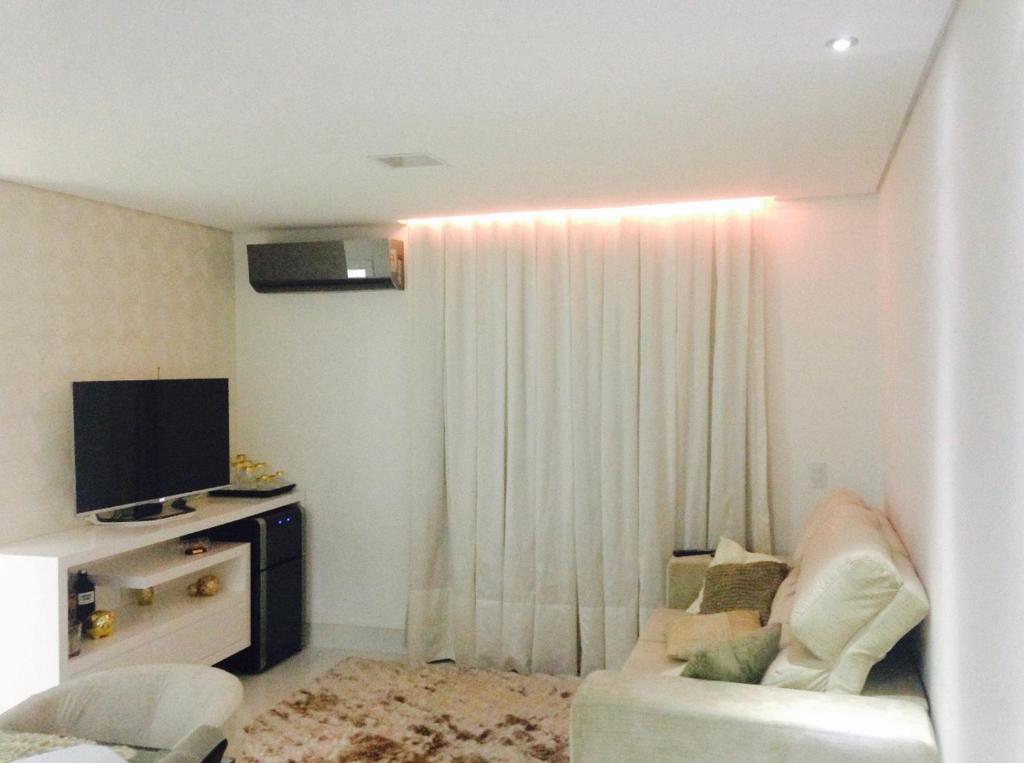 a living room with a couch and a television at Aconchegante apto em localização privilegiada in Cuiabá