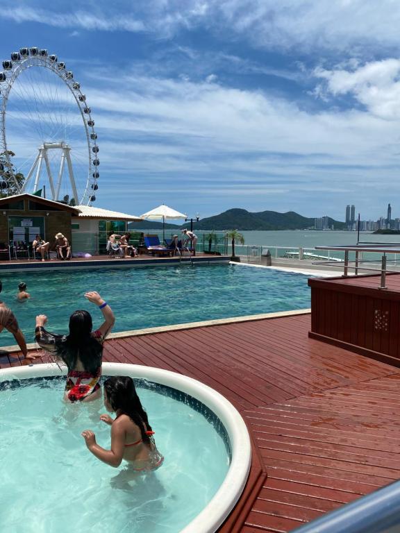 zwei Mädchen spielen in einem Schwimmbad in einem Resort in der Unterkunft "Conforto e Bem Estar" Próximo da praia in Balneário Camboriú