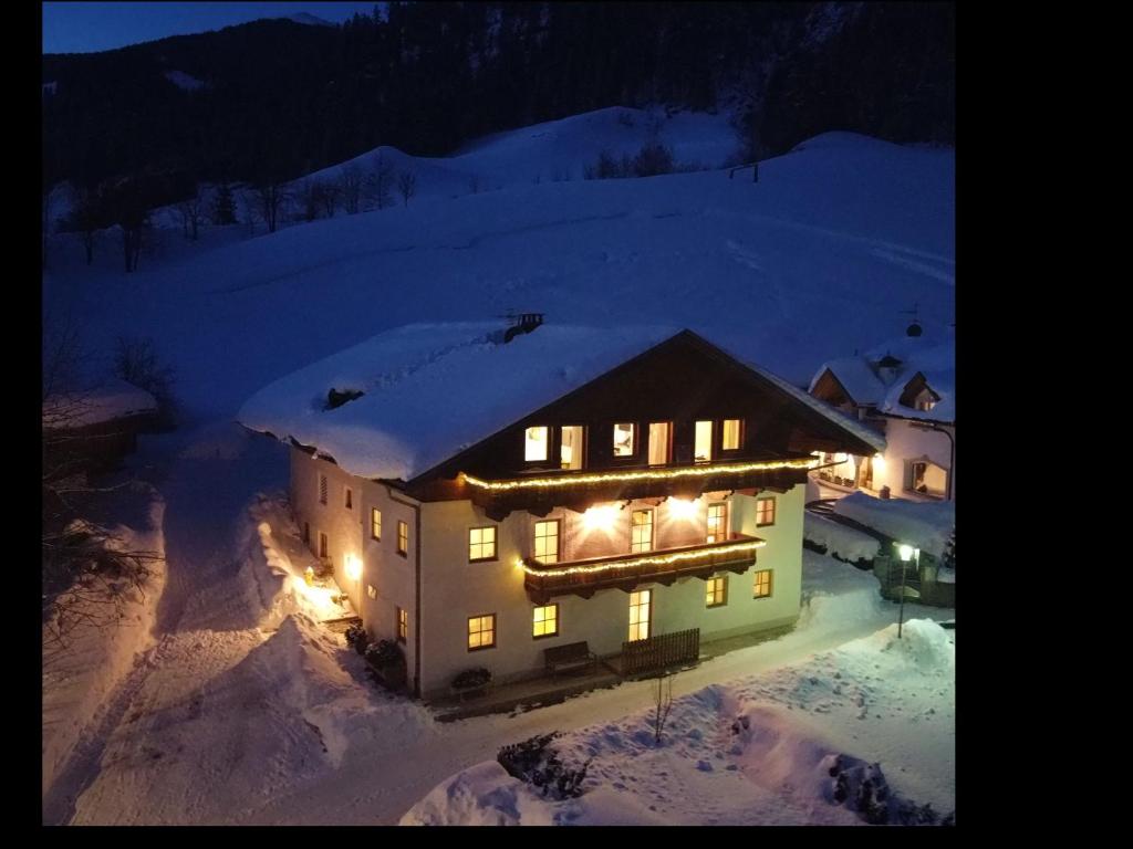 a house covered in snow at night with lights at Residence Tamperhof in San Candido