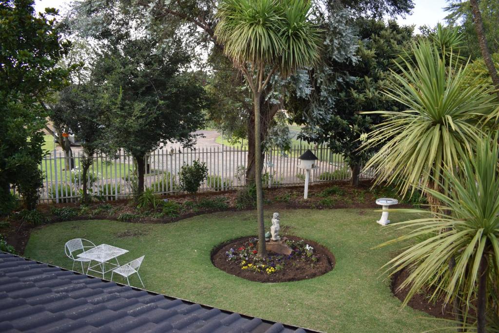 einen Garten mit einer Palme, 2 Stühlen und einem Brunnen in der Unterkunft Moye Guest House in Benoni