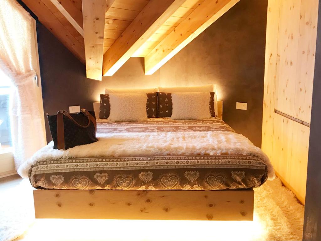 uma cama grande num quarto com tecto em madeira em Al Bait Del Legn 5 em Bormio