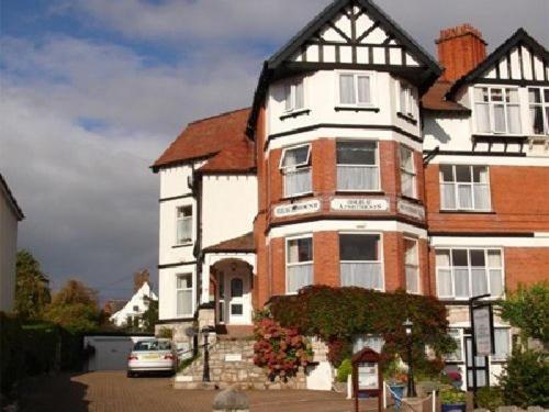 a large house with a car parked in front of it at Beachmount Holiday Apartments in Colwyn Bay