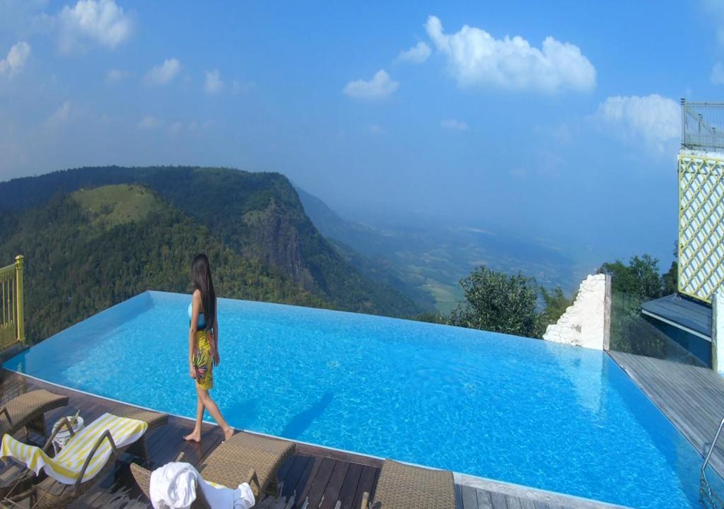 a woman standing on the edge of a swimming pool at Hills & Hues in Thekkady