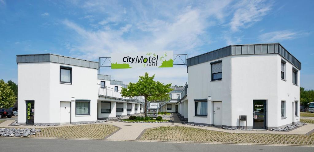 zwei weiße Gebäude mit einem Schild darüber in der Unterkunft City Motel Soest in Soest