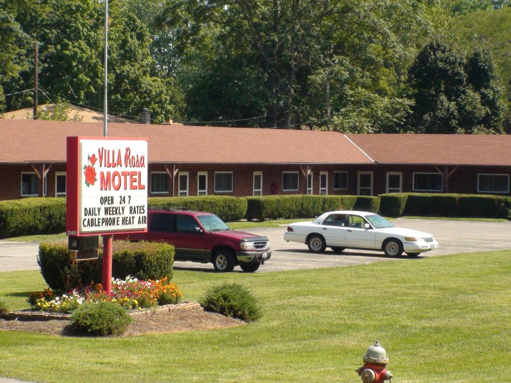 ein Schild vor einem Motel mit Autos auf einem Parkplatz in der Unterkunft Villa Rosa Motel in Painesville