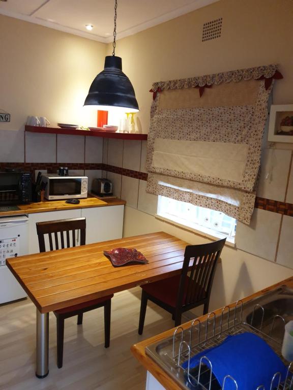 a kitchen with a wooden table and chairs in a kitchen at Blue Rain Guest House in Upington