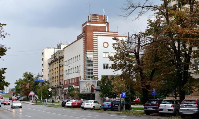 a city street with cars parked in front of a building at Exit Labirint Centar in Novi Sad