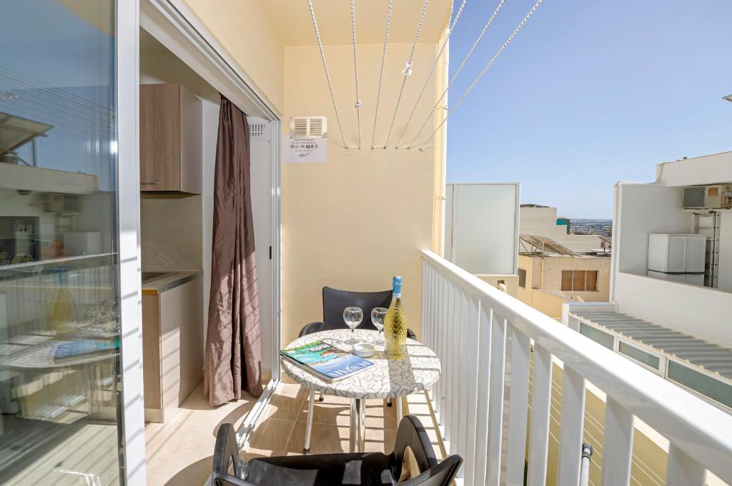 een balkon met een tafel en uitzicht op de stad bij Summer Breeze Comfort Sunny Apartments close to the sandy beaches - by Getawaysmalta in Mellieħa