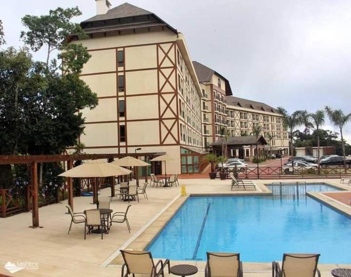 a hotel with a swimming pool and chairs and a building at Suite Cond Vista Azul em Pedra Azul - Domingos Martins in Domingos Martins