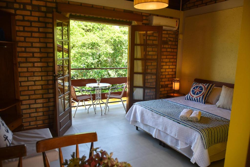 1 dormitorio con 1 cama y balcón con mesa en Pousada Portal Sul, en Florianópolis