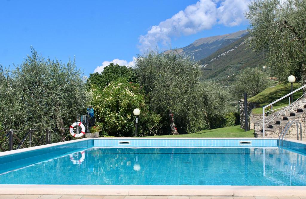 a blue swimming pool with mountains in the background at Appartamento Venzo in Brenzone sul Garda