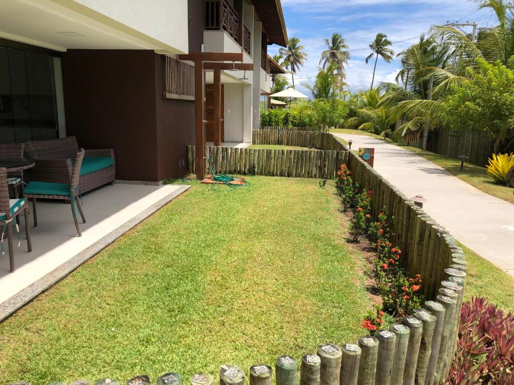 a backyard with grass and flowers and a fence at Ykutiba Residencial in Imbassai