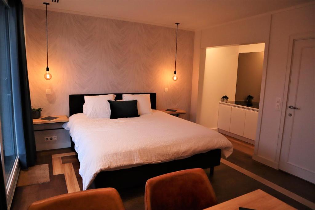 um quarto com uma grande cama branca e 2 cadeiras em B&B Fago em Bruges