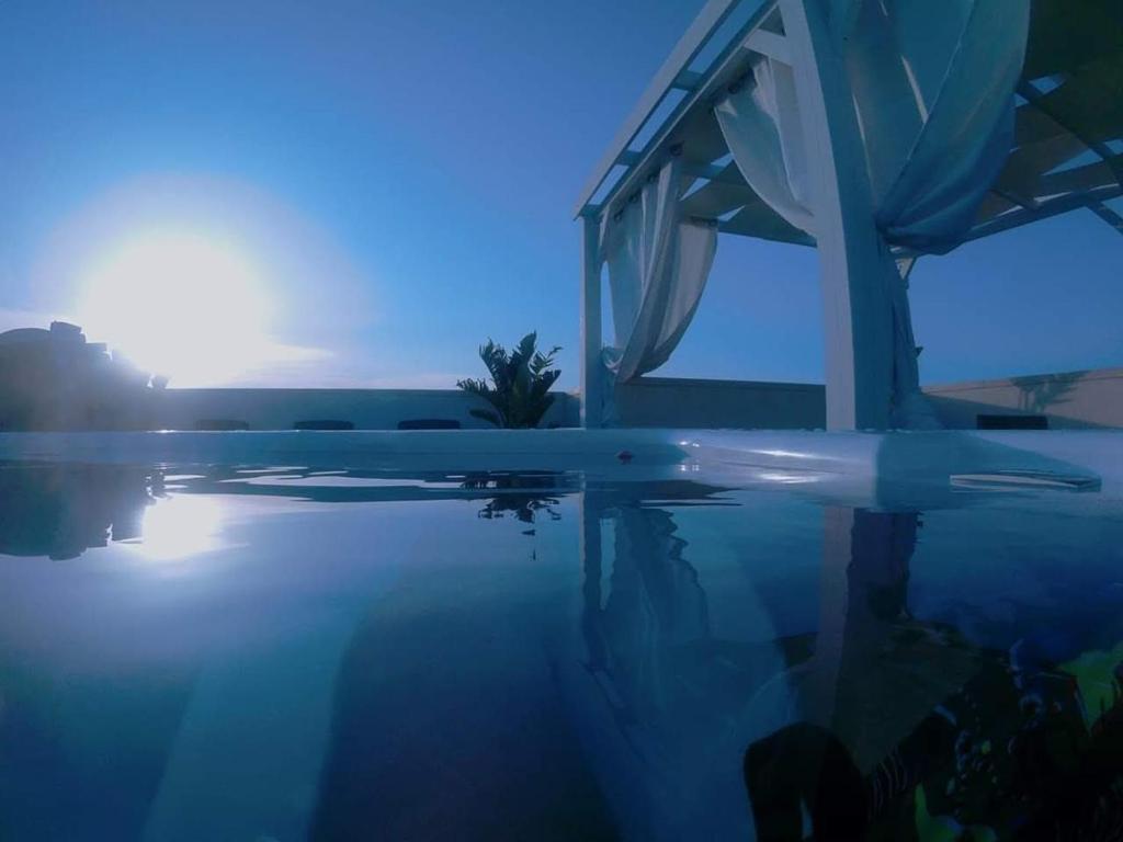 a swimming pool with the sun setting in the background at B&B Punta Stilo in Torre San Giovanni Ugento