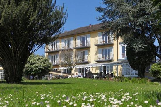 a large yellow building with trees and a field of flowers at Hotel Lindenallee in Lindau