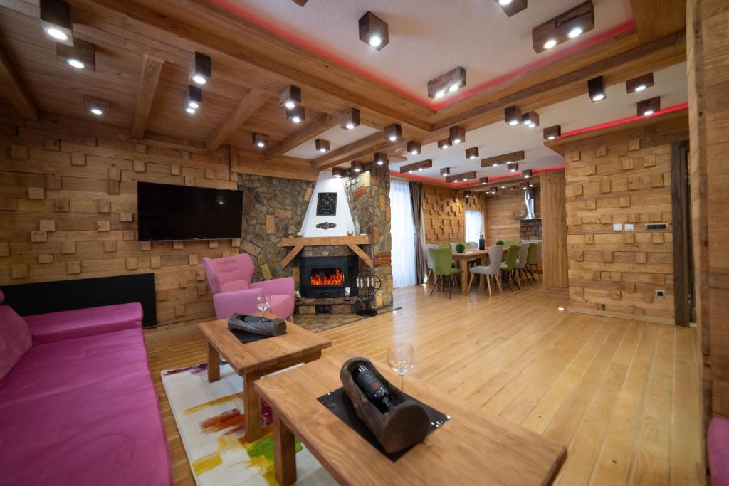 a large living room with a fireplace and a tv at Drugarska priča in Jahorina