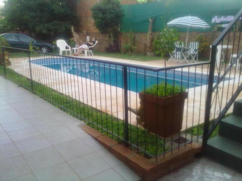 uma cerca em torno de uma piscina num quintal em Residencial Azaleas Place Guest House em Puerto Iguazú