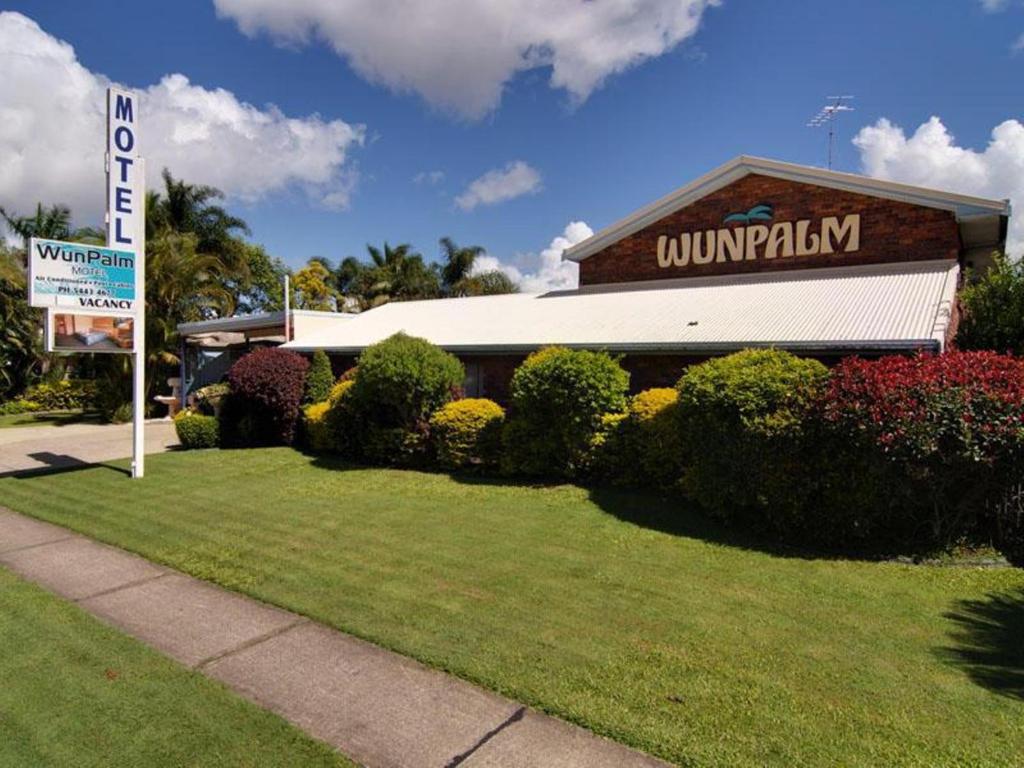 a large white building with a sign on the side of it at Wunpalm Motel & Holiday Cabins in Maroochydore