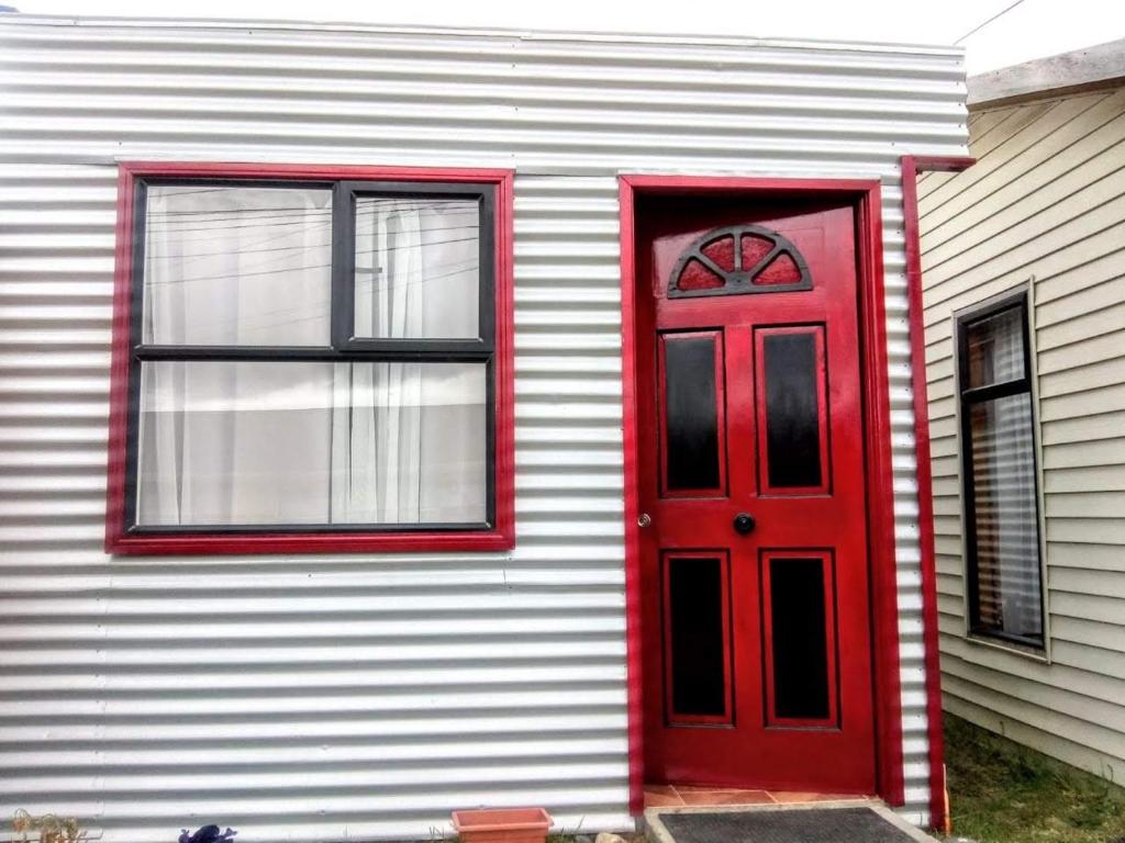una puerta roja al lado de una casa en Cabaña Gesell, en Puerto Natales