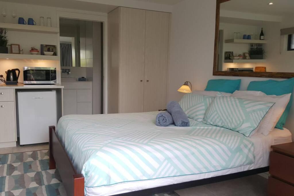 a bedroom with a large bed and a kitchen at Woolloongabba, comfortable, modern, private studio in Brisbane