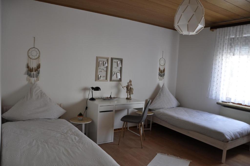 a bedroom with two beds and a desk and a chair at Super zentral und dennoch idyllisch und erholsam in Dreieich