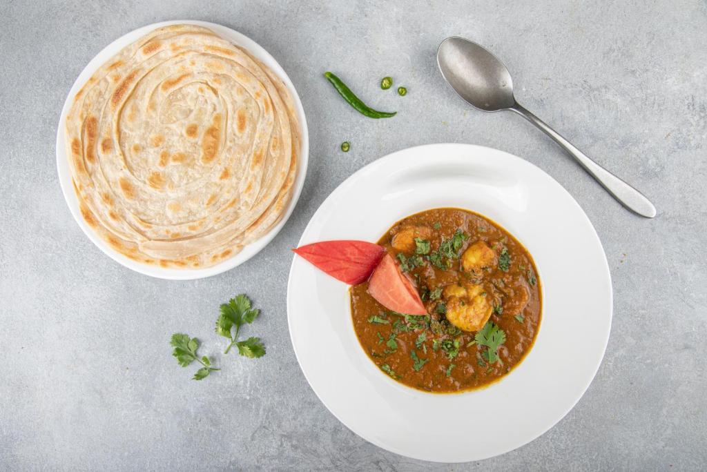 a plate of food with a bowl of stew and a bowl of soup at Flamingo Beach Hotel in Umm Al Quwain
